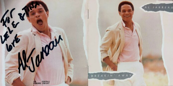 Al Jarreau - la copertina del disco con il cantante di colore con capelli ricci neri, indossa pantaloni bianchi, t shirt rosa e giacca beige chiara. Ha le mani in tasca