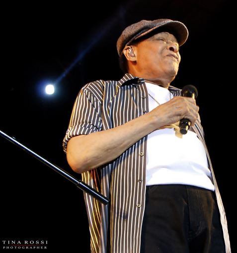 al jarreau in concerto, indossa una t shirt bianca, pantaloni neri e camicia a riche