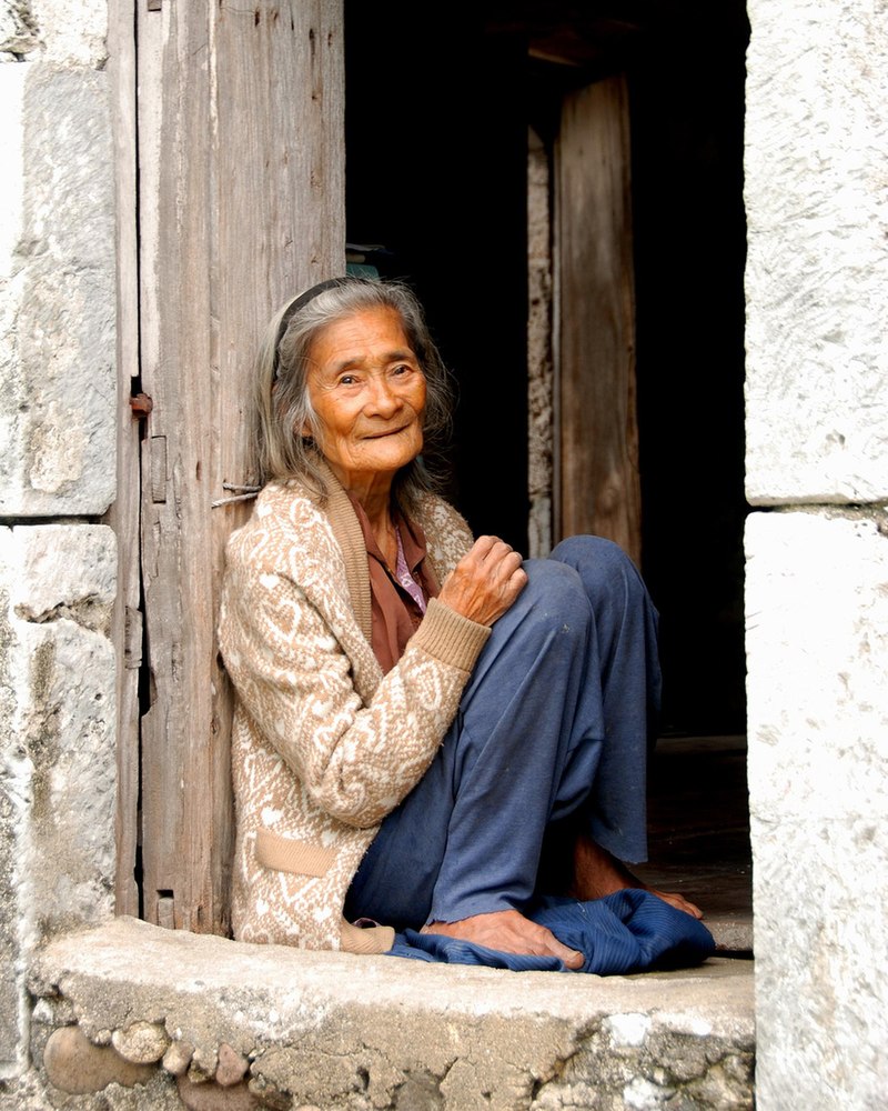 una donna anziana seduta sulla soglia della casa in vietnam