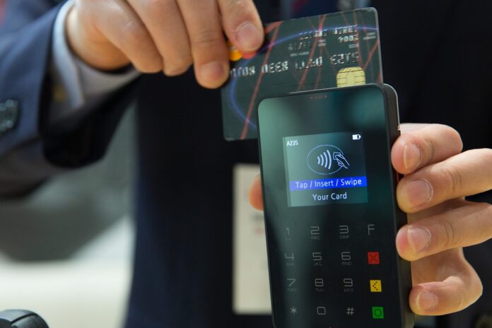 Pagamenti elettronici - un uomo sta strisciando la carta di credito in un POS