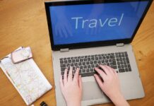 Booking - un laptop aperto con la schermata blu conla scritta "Travel", di fianoc, un acartina geografica