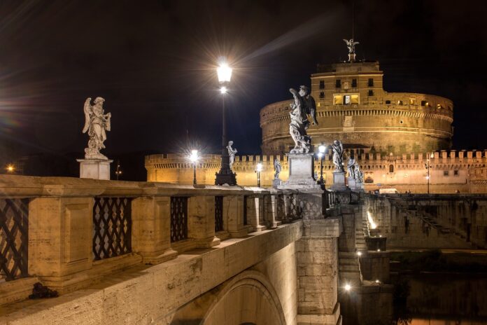 Castel sant'Angelo a Roma - vista notturna dal ponte con tante statue. Il castello è rotondo sovrastato da una torre sormontata dalla statua di un angelo