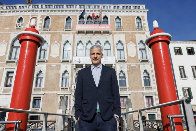 Adriano Pedrosa, Photo by Jacopo Salvi, Courtesy of La Biennale di Venezia la foto è davanti a palazzo ducale con due approdi rossi Pedrosa in piedi con vestito nero