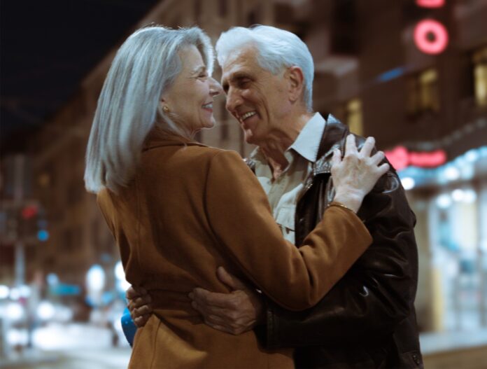 almeno credo - la copertina del nuovo singolo di dile che raffigura un uomo e una donna di mezza età abbracciati per strada di sera