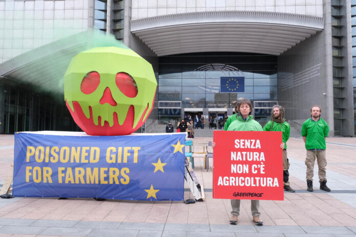 norme ambientali. Greenpeace activists installed a giant poisoned apple outside the European Parliament in Brussels, urging politicians in the parliament not to give farmers a poisoned gift by scrapping nature protection rules in the common agricultural policy (CAP). Members of the European Parliament are today deciding whether to rush through a vote on the European Commission’s plan to remove many of the environmental requirements farmers must meet to get EU funds.