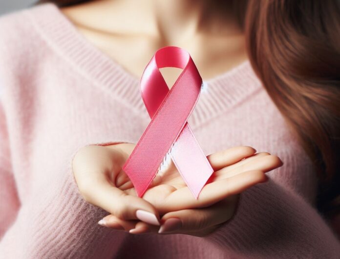 tumore del seno - il primo piano della mano di una donna che tiene in mano un fiocchetto rosa simbolo della prevenzione