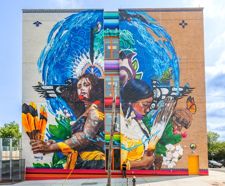 flusso indigeno un indiana e una persona migrante amarica sulla facciata di un palazzo opera Street art