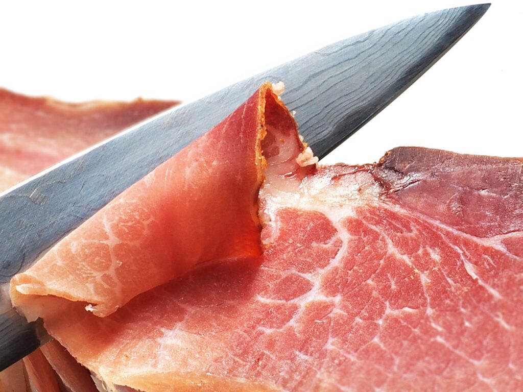 Friuli  Friuli Venezia Giulia - cucina friulana - un coltello sta tagliando una fetta di prosciutto crudo
