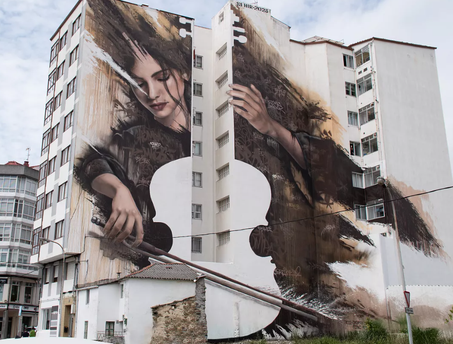 street art una donna su un palazzo che suona il violoncello 