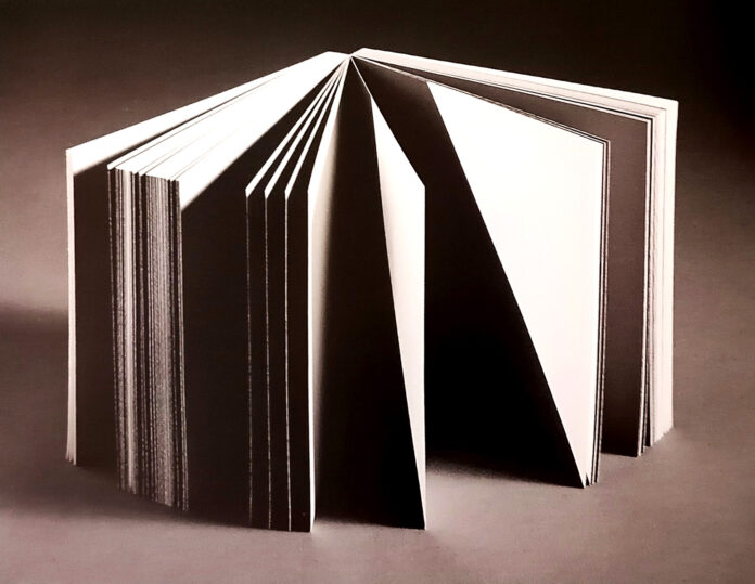 un libro disposto in verticale, aperto, le pagine sono metà bianche e metà nere