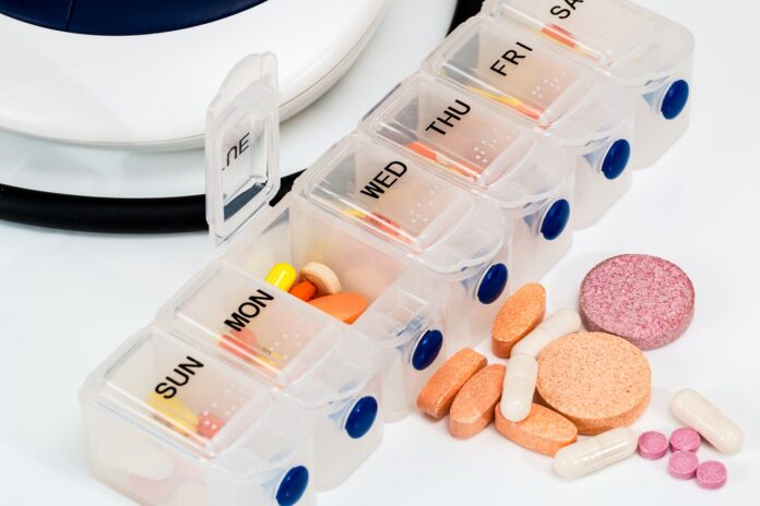 Farmaci generati con IA - nella foto una scatola con i giorni della settimana scritti su ogni casella che contiene delle pillole. Fuori dalla scatola delle pastiglie sparse