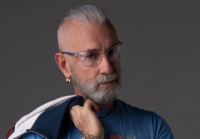 la colegiala revolution - gary low in primo piano, barba e capelli brizzolati, indossa una camicia blu