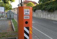 una colonnina arancione dell'autovelox posizionata su una strada