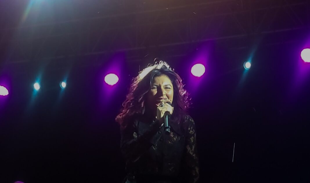 Giusy Ferreri in primo piano, vestita di scuro, durante un concerto