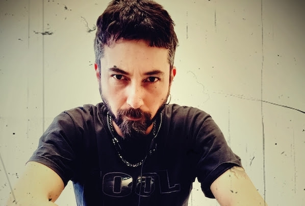 tony pastello - il cantautore yanez in primo piano, ha la barba e i capelli scuri e indossa una t shirt nera