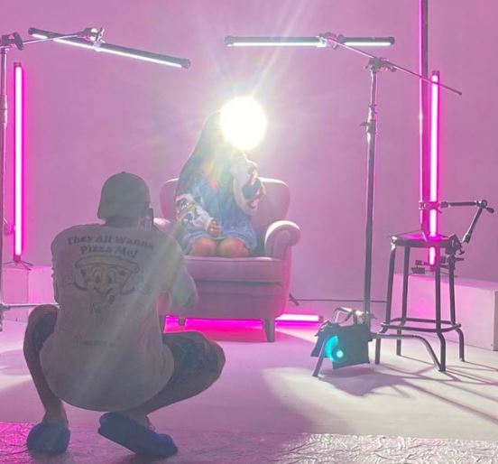 silvia carrino in controluce, seduta su una sedia, mentre viene fotografata da un fotografo, di spalle
