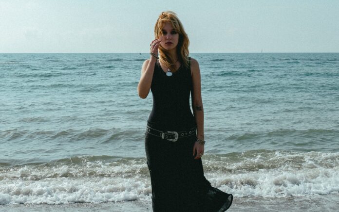 giin, vestita di scuro, fotografata in riva al mare.