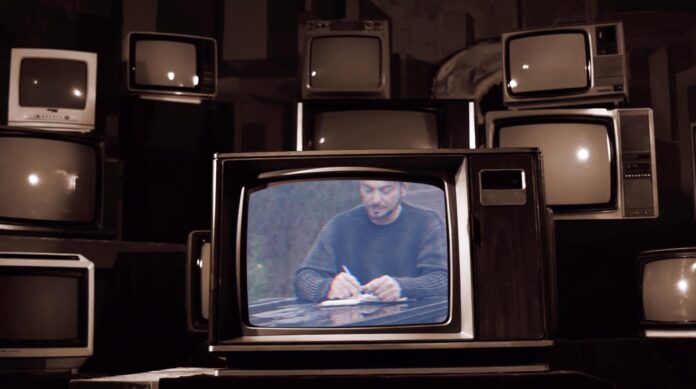 giuseppe cucè in primo piano, circondato da televisori vintage
