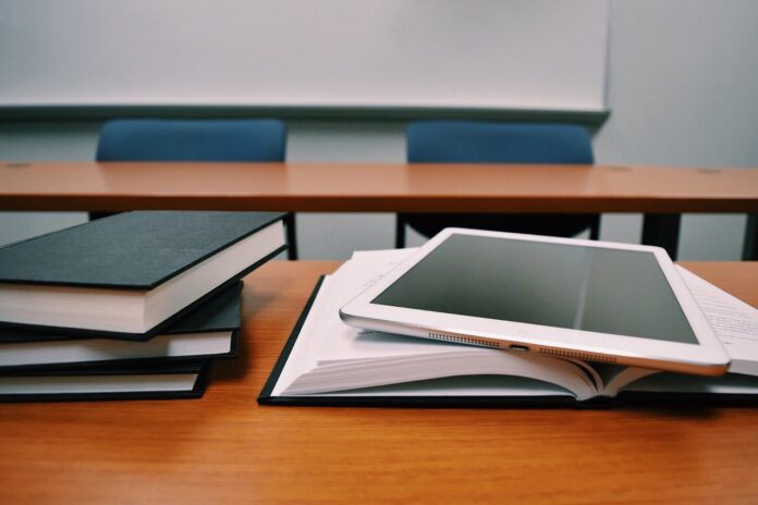 dei libri su un banco di scuola e sullo sfondo si capisce che ci sono altri banchi e di essere in un'aula scolastica