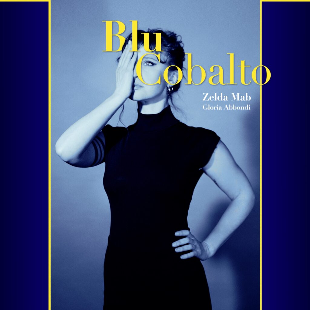 gloria abbondi - la copertina del nuovo singolo che la ritrae in piedi, in primo piano, vestita di scuro