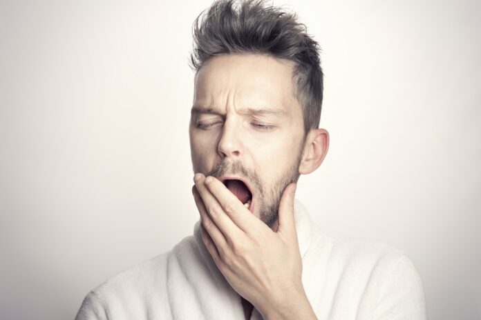 Cambio di stagione stanchezza primavera - un uomo con capelli corti sta sbadigliando