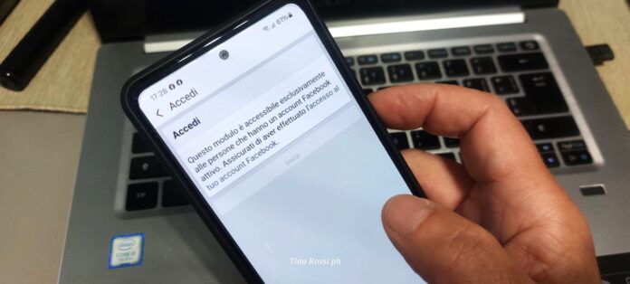 Come negare consenso Meta AI su facebook ecco i link - uina persona tiene in mano un telefonino che ha la schermata sulla pagina di facebook e dietro un laptop