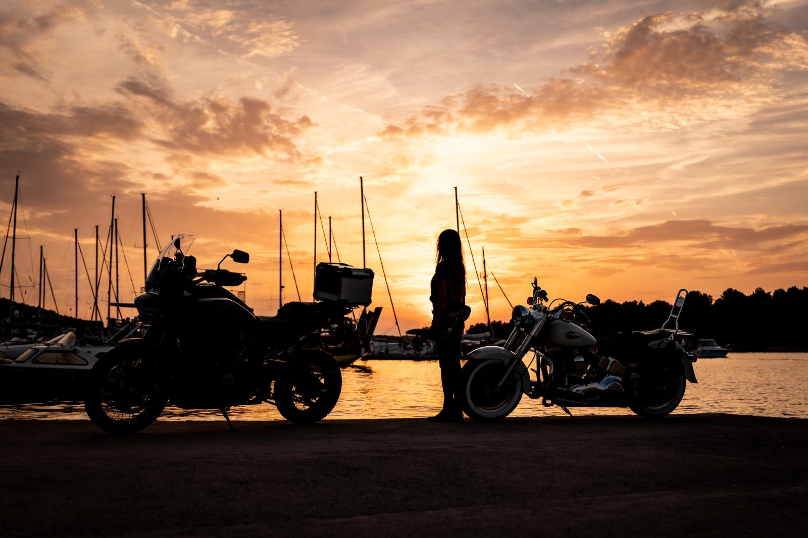 Il Rally Europeo H.O.G. 2025 arriva a Medulin - nella foto due harley davidson in controluce, parcheggiate sulla banchina del porto