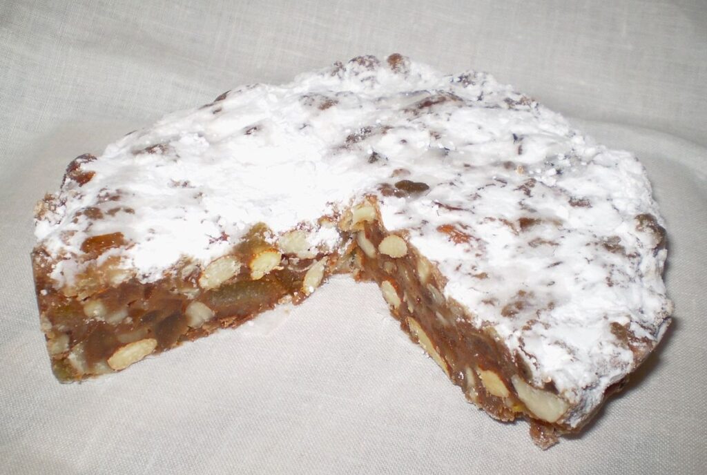 un dolce rotondo con dello zucchero a velo sopra e tante mandorle dentro