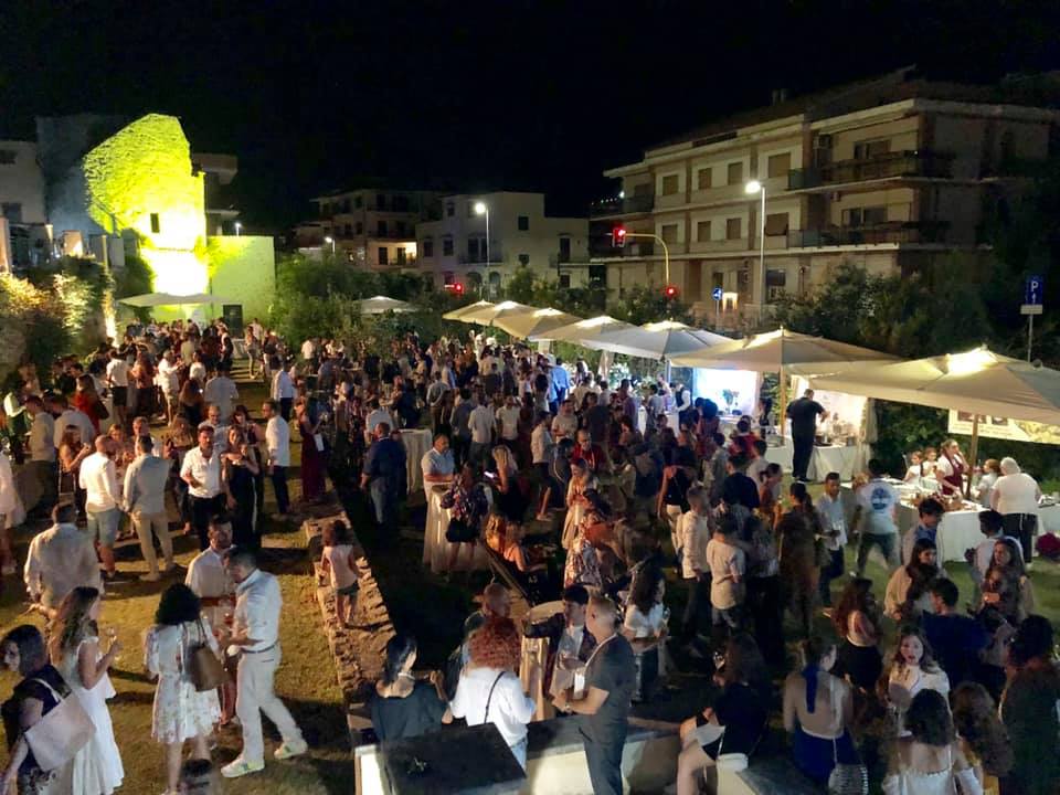 tanta gente di sera che passeggia tra gli stand di una fiera gastronomica