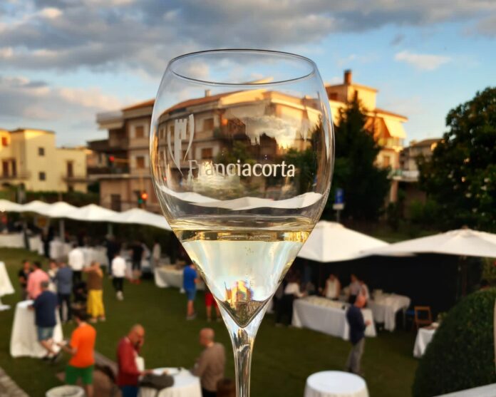 Franciacorta in Villa - nella foto in primo piano un calice di vono bianco e sullo sfondo la villa e sotto sfocata la gente