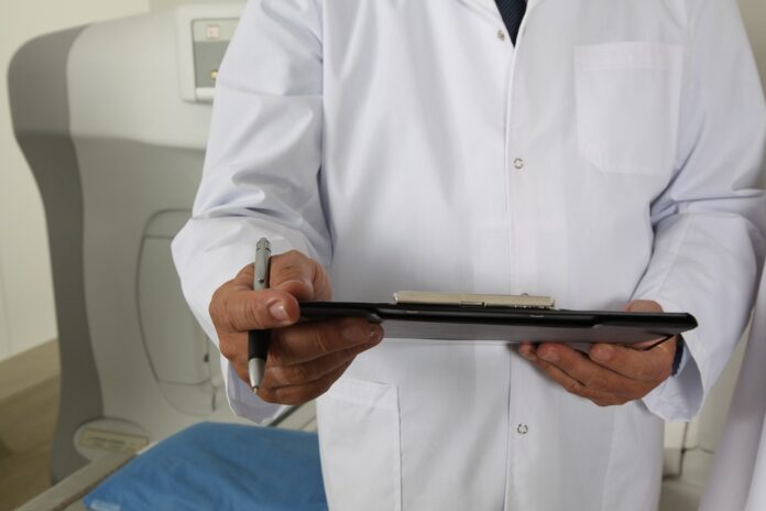 Tumore e terapia del dolore - nella foto il busto di un medico con camice bianco che tiene in mano una cartellina e una penna