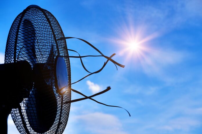 caldo estivo emergenza caldo - un ventilatore puntato verso il sole nel cielo, fa volare delle strisce di stoffa