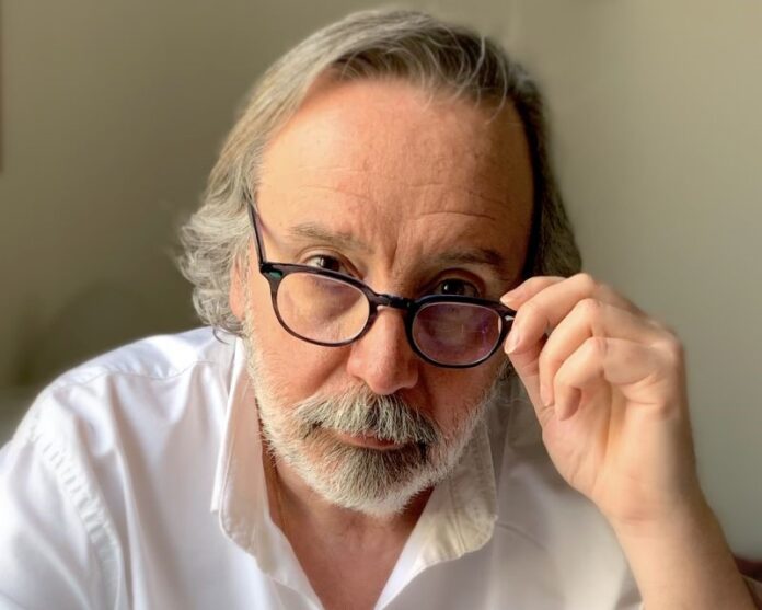 Editori e uffici stampa sui libri sventola bandiera bianca - primo piano di un uomo con barba e capelli bianchi, lunghi, occhiali che si tocca con una mano