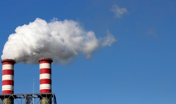 Giustizia climatica storica sentenza delle Sezioni Unite della Cassazione - nella foto due ciminiere con strisce rosse e fumo bianco che sale verso il cielo azzurro