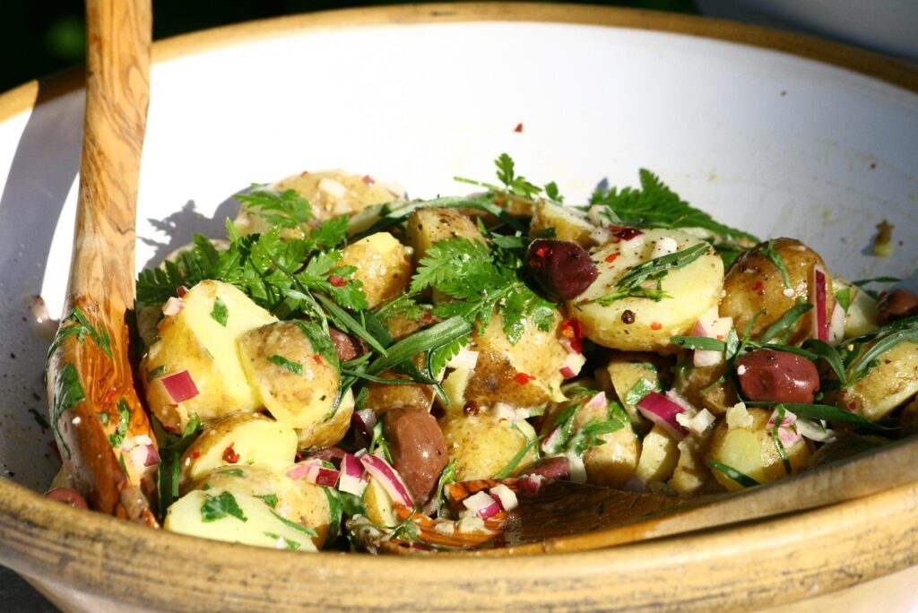 insalata di patate acciughe prezzemolo e peperoncino in una ciotola bianca