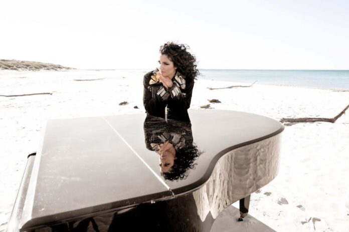 isabella turso appoggiata a un pianoforte sulla spiaggia