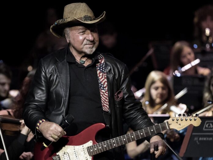 pietruccio montalbetti, giacca di pelle nera e cappello di paglia da cawboy, buraante un concerto