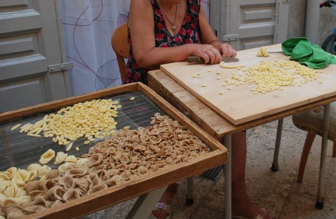 la guerra delle orecchiette pastaie Bari Vecchia - nella foto tante orecchiette di pasta su un setaccio rettangolare grande appoggiato ad un tavolo di legno