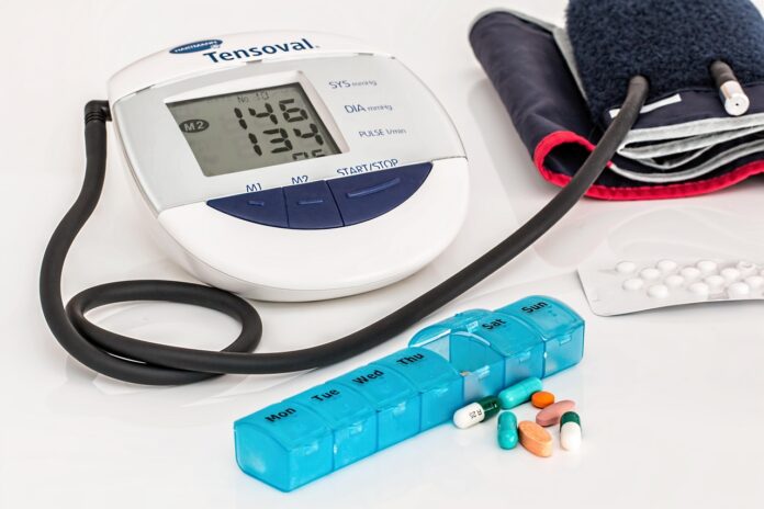 Pressione alta, pericolo d'infarto e diabete le truffe sulla salute - nella foto un misuratore di pressione a braccio, un porta pillole blu e delle pillole sparse sul tavolo