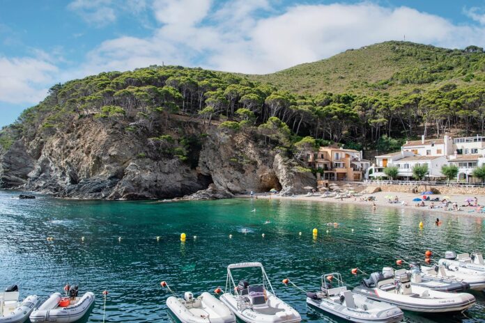 Vacanze - una panoramica di un acaletta di mare, con la spiaggia, il golfo, la montagna e tante barche attraccate con gente in mare