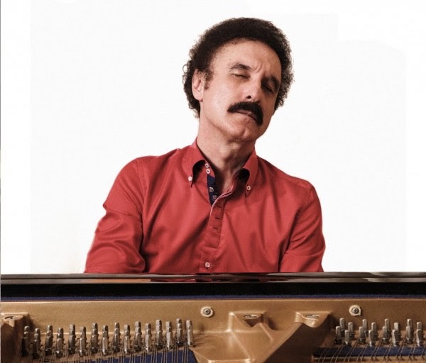 Gino Di Iorio racconta la sua Una vita in musica nel nuovo album - Zetatielle Magazine gino di iorio in primo piano, indossa una camicia rossa ed è intento a suonare il pianoforte