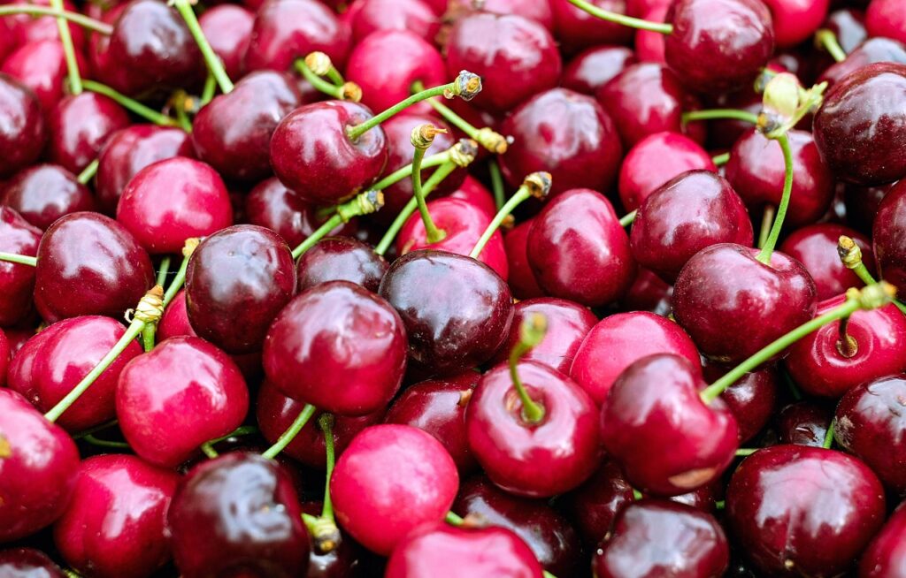 Molti frutti rossi e lucidi, appena raccolti e ammassati insieme.