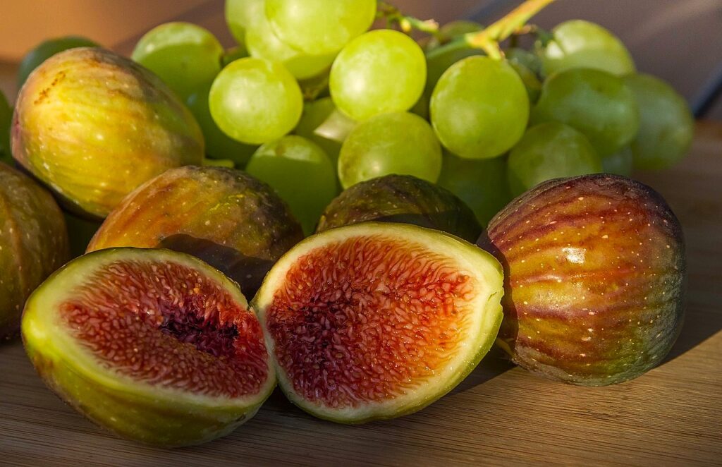 fichi e uva: iu fichi sono apeerti in due e mostrano la polpa rossa , l'uva è a grappolo ed è bianca