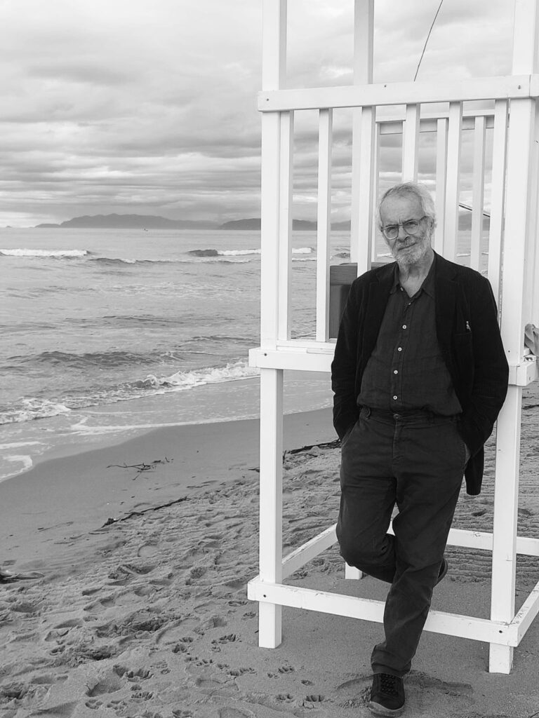 ludovico einaudi - Enzo gentile vestito di scuro fotografato in spiaggia