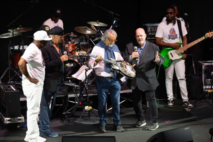 graziano uliani sul palco, circondato da musicisti, ha in mano una chitarra dobro