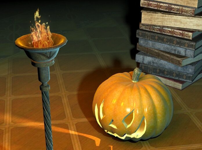 Letture per Halloween chi ha paura delle streghe - Zetatielle Magazine - halloween-506441_1280 letture per halloween streghe - nella foto a fumetto su un pabvimento di legno è appoggiata una zucca intagliata con naso occhi e bocca e illuminata dall'interno, dietro dei libri a catasta e di fianco una torcia accesa