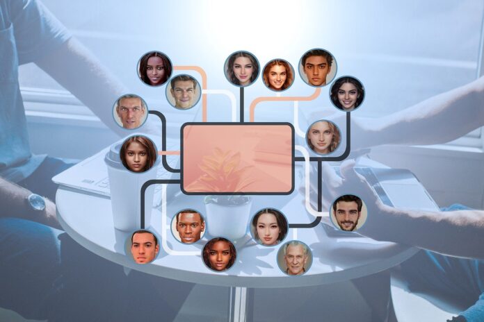 Chat di gruppo Open AI - nel mezzo un rettanglolo arancione da cui partono linee che arrivano a pallini con dentro la foto di persone e sullo sfondo sfocato un tavolo rotondo su cui ci sono due pc portatili e si intravedono due persone che scrivono sulla tastiera