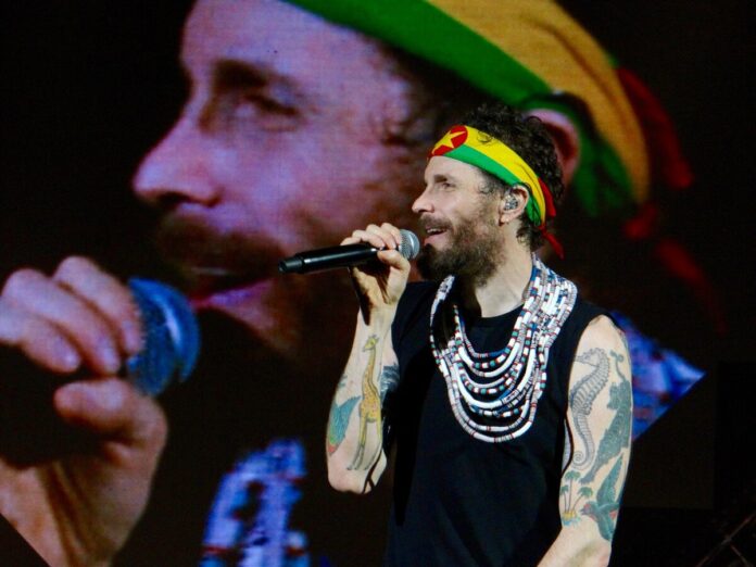 il caso Jovanotti, quando la tutela diventa gabbia - Zetatielle Magazine - Jovanotti__Lorenzo_nei_Palasport__-_24046936530 Jovanotti canta con microfono in mano, indossa canottiera nera, fascia tricolore giallo rosse e verde sui capelli, ha tatuaggi sul corpo, dietro di lui un grande schermo che riproduce la sua immangine
