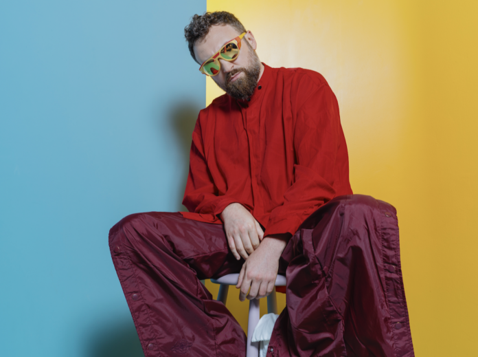 dargen d'amico in primo piano indossa maglione rosso e pantaloni larghi viola - sanremo 2026