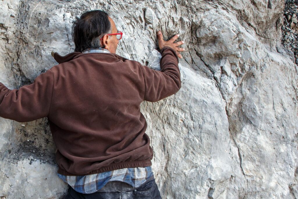 dinosauri - una impronta e un uomo che mette la mano dentro per dimostrare la differenza di taglia